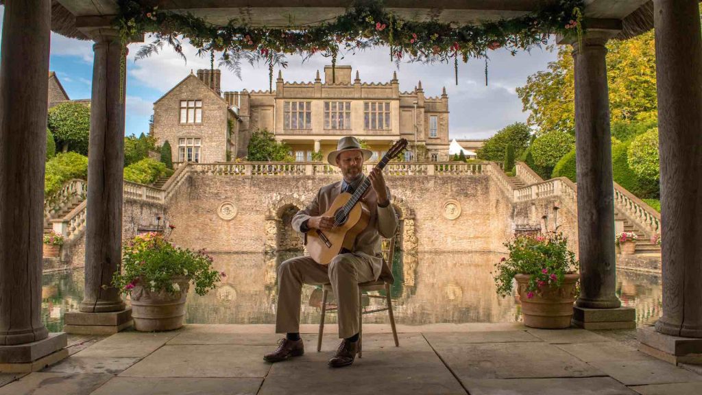 Wedding guitarist playing in gazebo by pond.