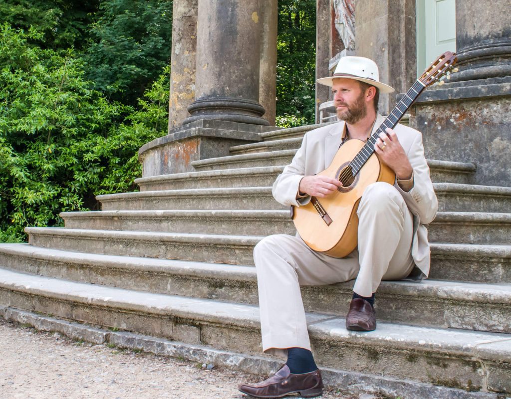 Live Musician Classical guitarist in suit sitting on temple steps